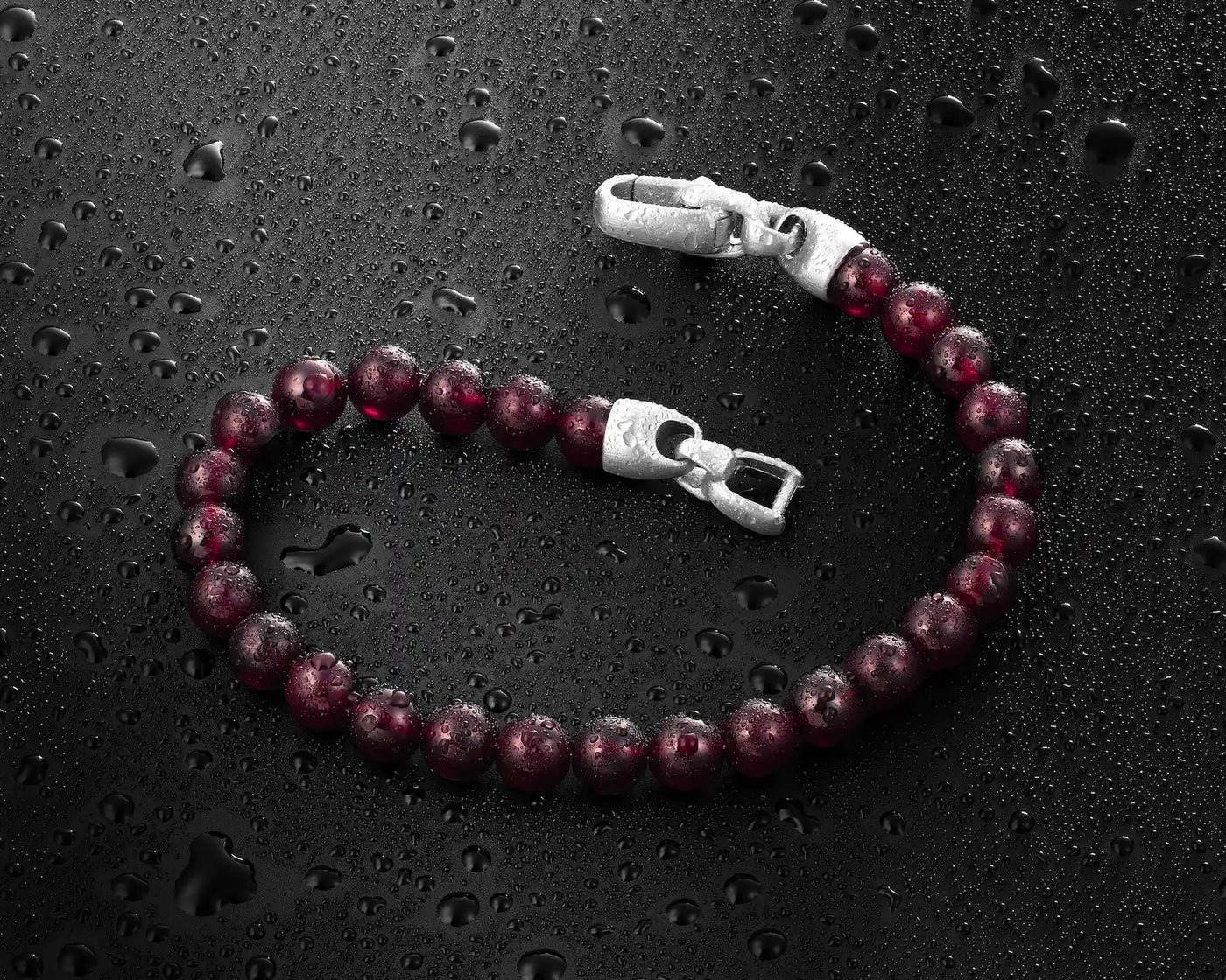 Beaded bracelet with silver clasp on a dark textured surface