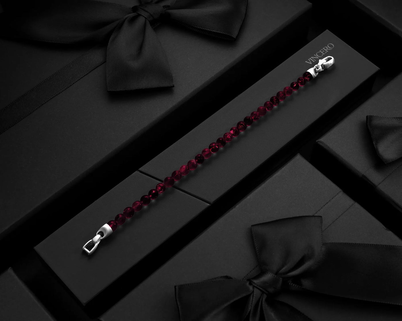 Garnet bracelet with silver clasp on a dark surface with black ribbons