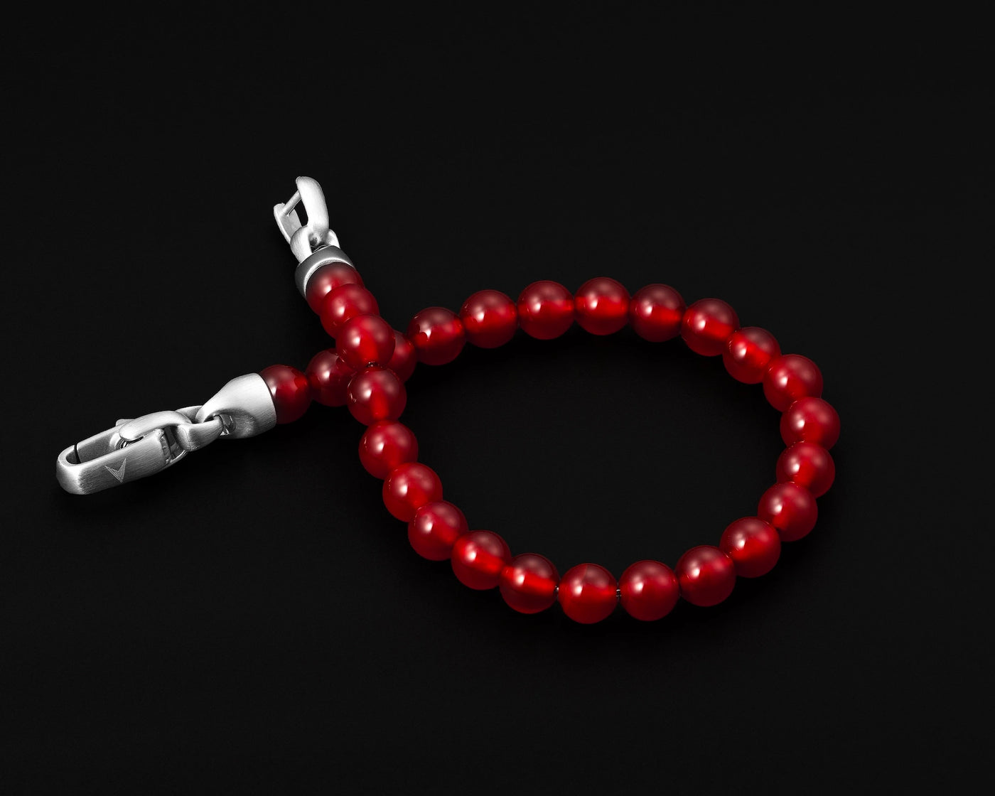 Red beaded bracelet with silver clasp on a black background