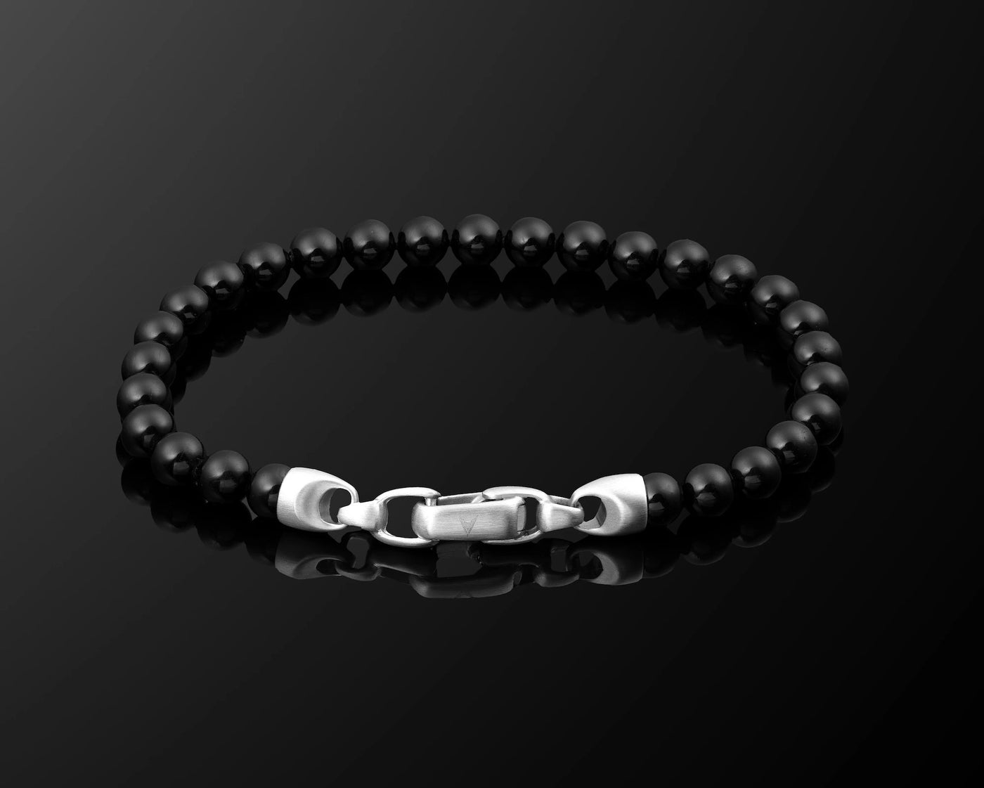 Black beaded bracelet with a silver clasp on a black background