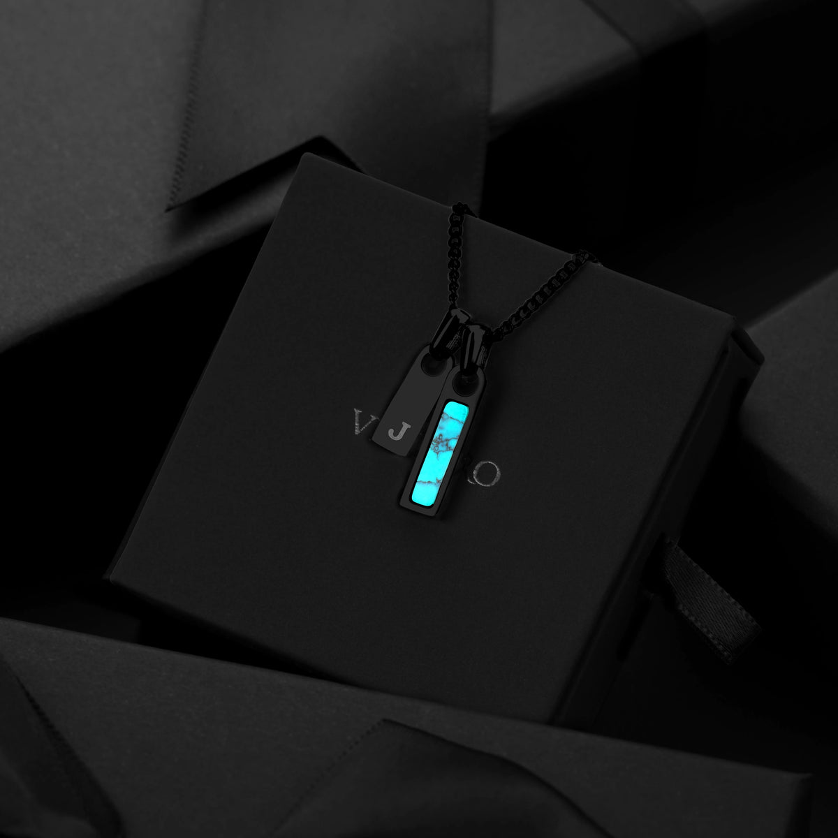 Necklace with pendant on a black box against a dark background