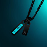 Necklace with a black chain and two tags, one turquoise and one black, on a dark blue background.