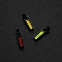 Three small rectangular pendants
 with colorful interior on a dark textured surface