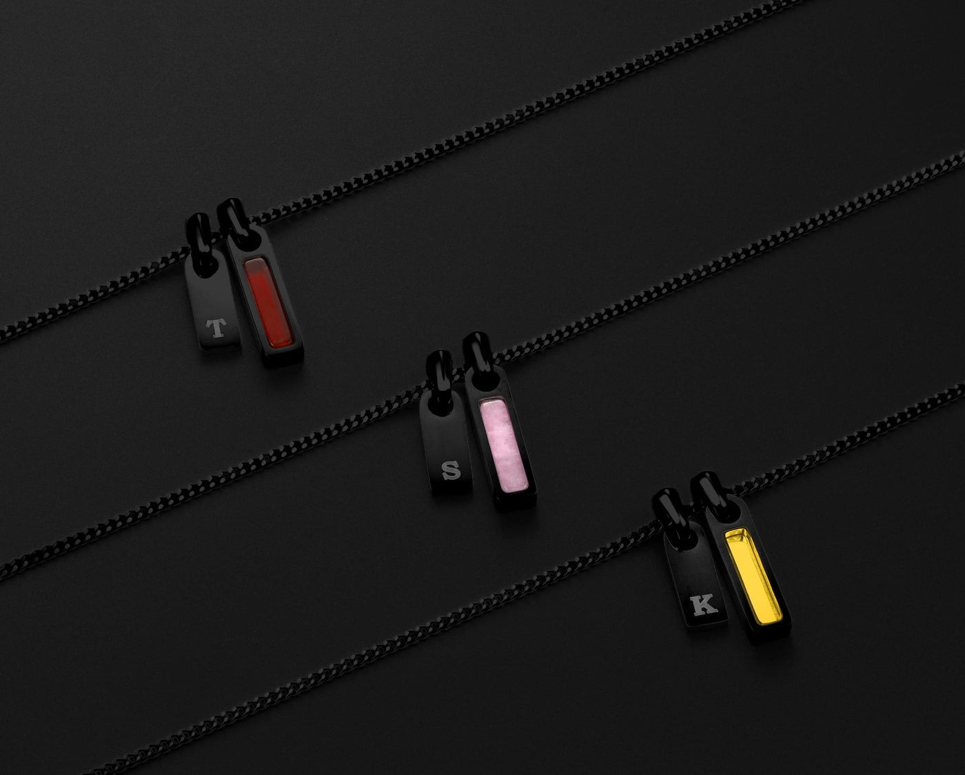 Three black zip pullers with colored accents on a black background