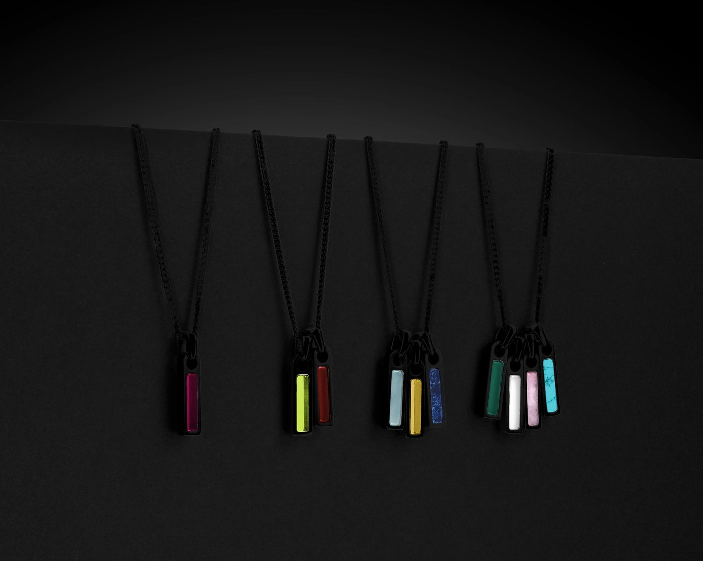 Set of five necklaces with colorful pendants on a black background
