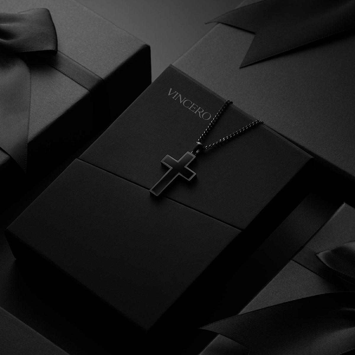 Black cross pendant displayed on black packaging
