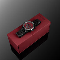 Watch with black strap and red face on a red box against a gray background