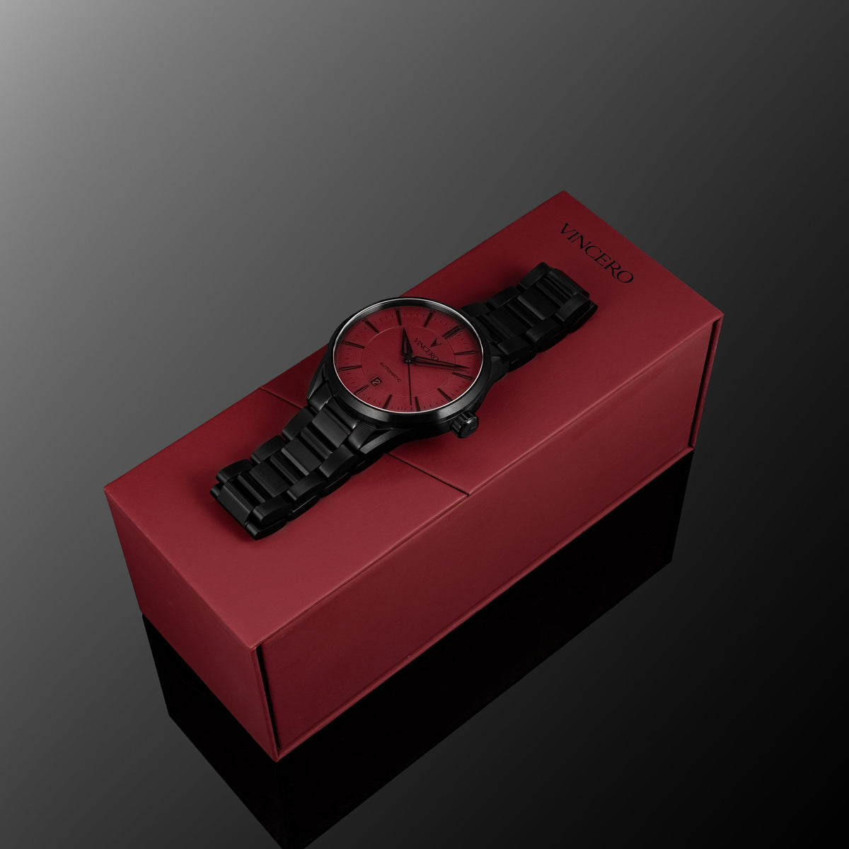 Black watch with red face on a red box against a gray background