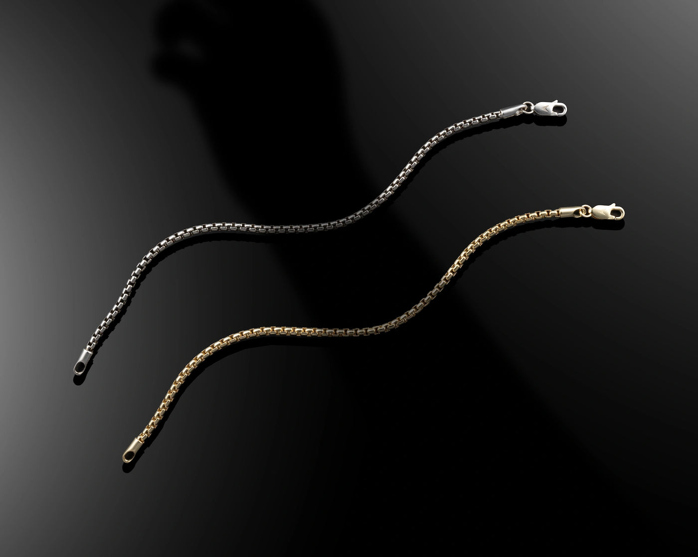 Two gold necklaces on a black background