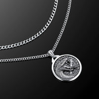 Silver necklace with a detailed pendant on a black background