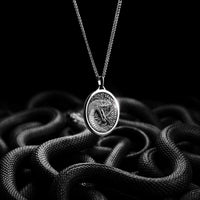 Silver snake pendant necklace on a black background