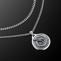 Silver necklace with a round pendant on a black background