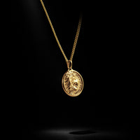 Gold necklace with a pendant on a black background