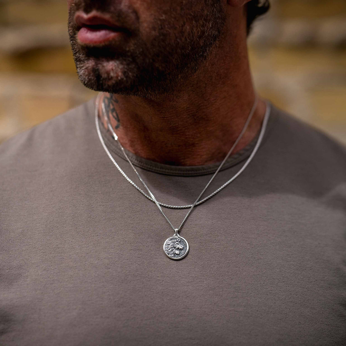 Man wearing a silver chain necklace with silver lion pendant
