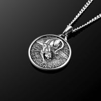 Silver pendant necklace with engraved design on a black background