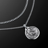 Silver necklace with a coin pendant on a black background