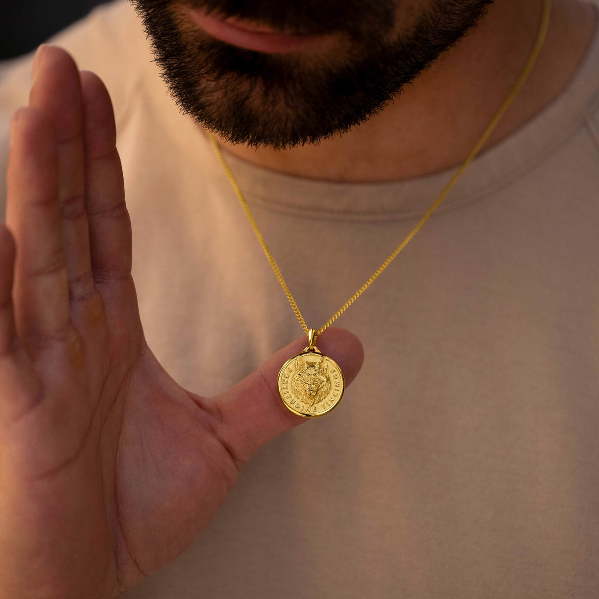 Man holding a gold necklace with a pendant