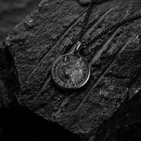 Black wolf pendant for man on black lava rock with scratches 