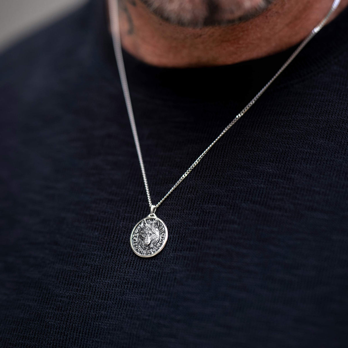 Man wearing silver chan necklace with silver wolf pendant 