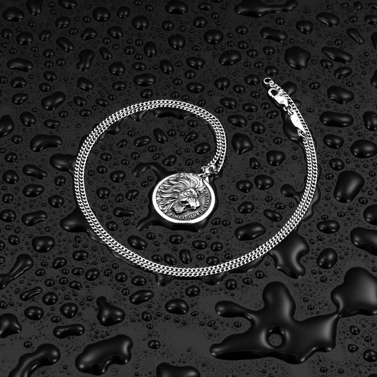 Silver chain necklace with a lion pendant on a black textured surface.
