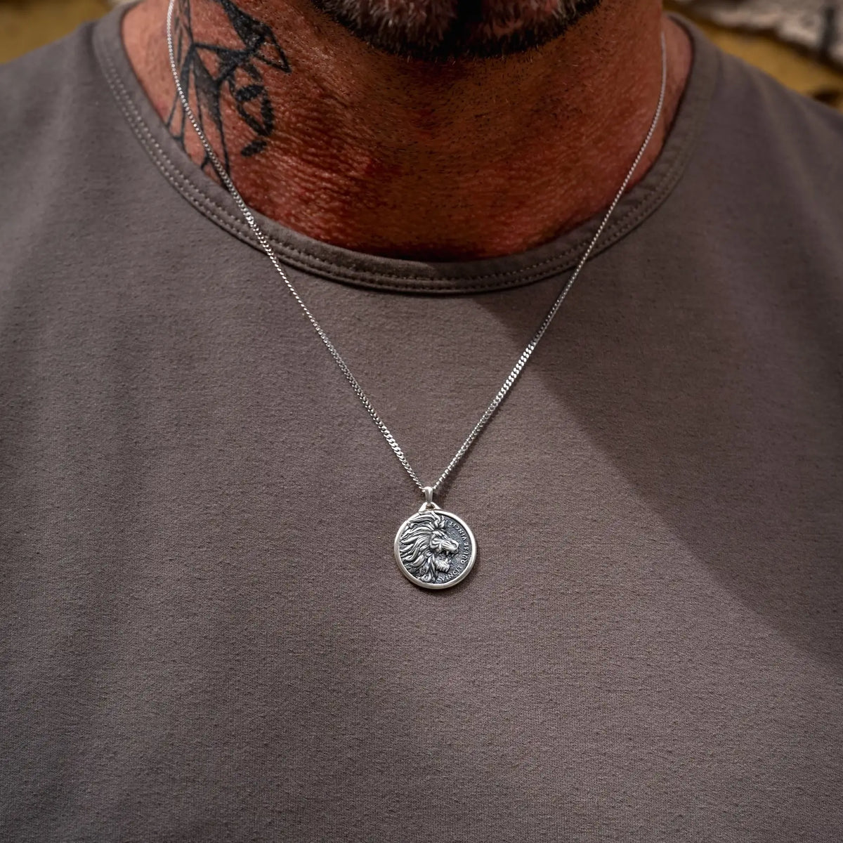 Silver necklace with a pendant on a person wearing a gray shirt.