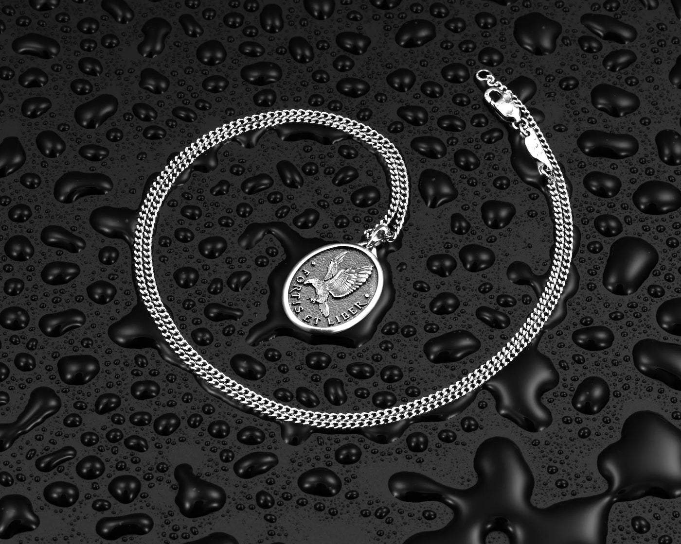 Silver chain necklace with silver eagle pendant, surrounded by water droplets.