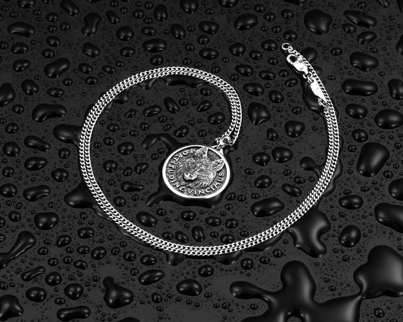 Silver chain necklace with silver wolf pendant, surrounded by water droplets. 
