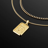 Gold necklace with a rectangular pendant on a black background