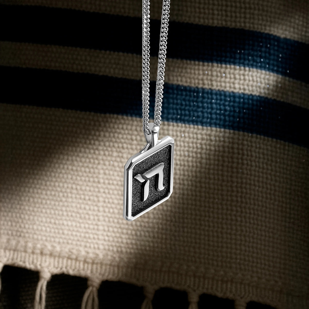 Silver necklace with a pi symbol pendant on a textured fabric background