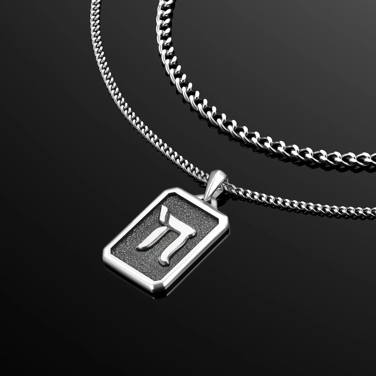 Silver necklace with a pendant featuring a symbol on a black background