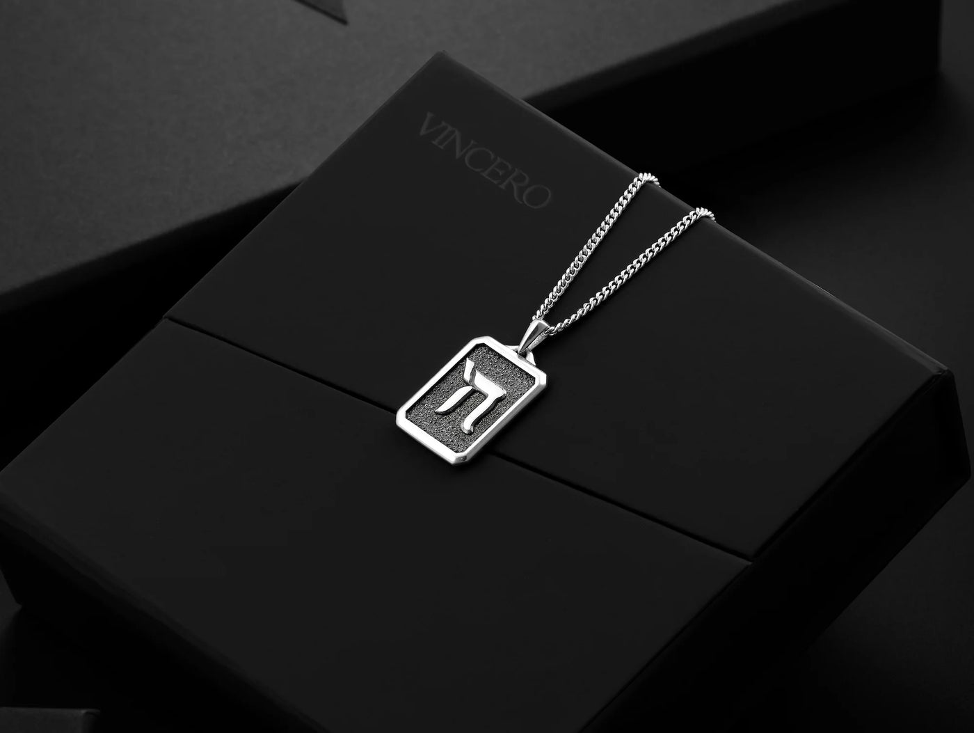 Silver necklace with a pendant on a black box, featuring the brand 'Vincero'.