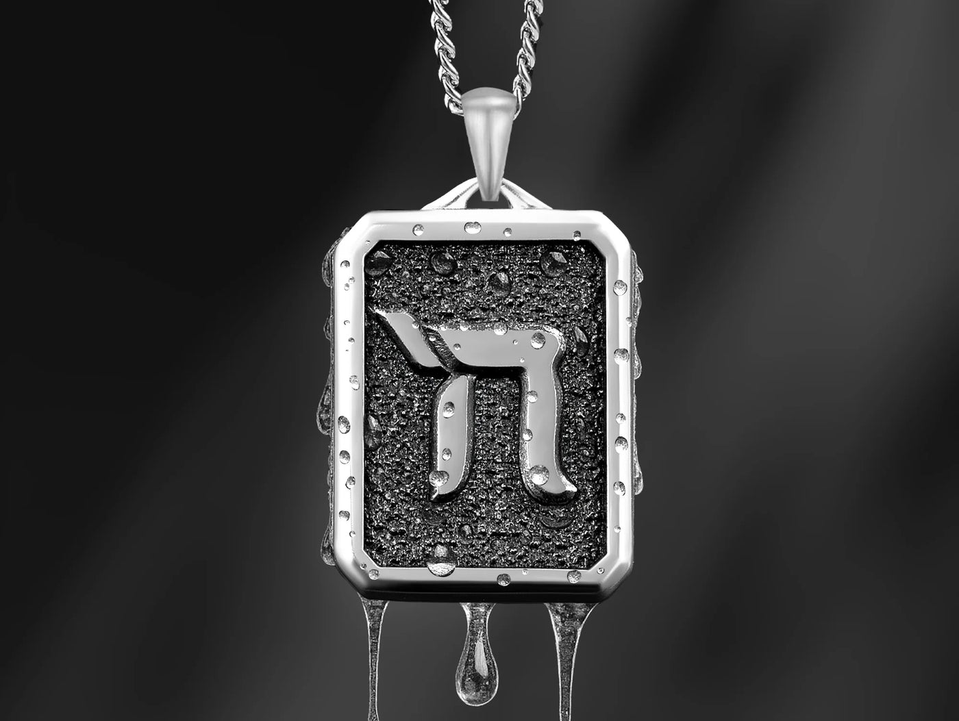 Silver pendant with a Hebrew letter on a dark background