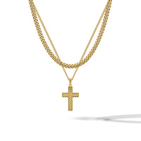 A gold layered necklace set featuring a thick curb chain and a delicate chain with a textured cross pendant, displayed against a clean white background with a soft shadow.