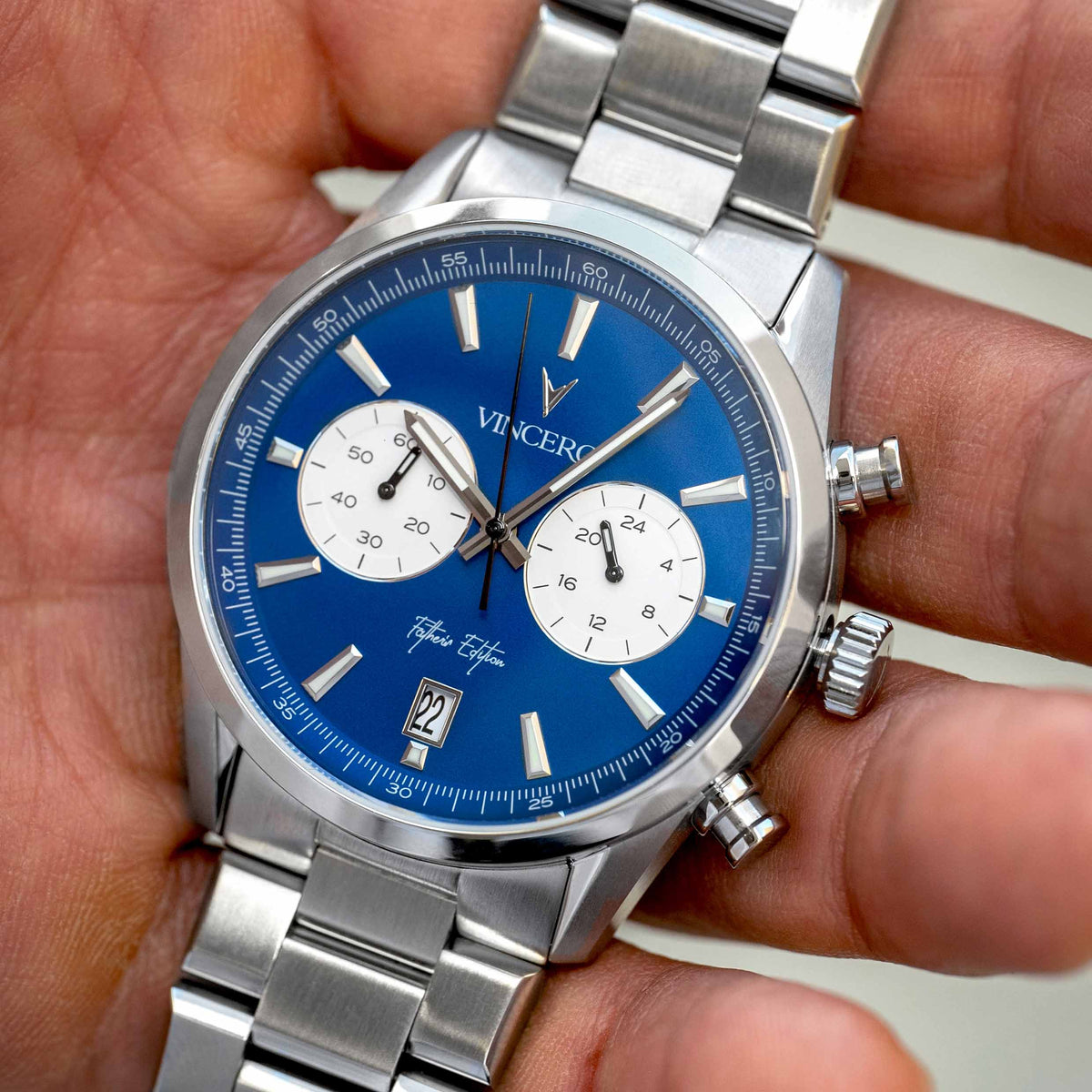 Close-up of a Father’s Day Edition watch, featuring a blue face, stainless steel casing, and steel band, displayed in a man's hand.