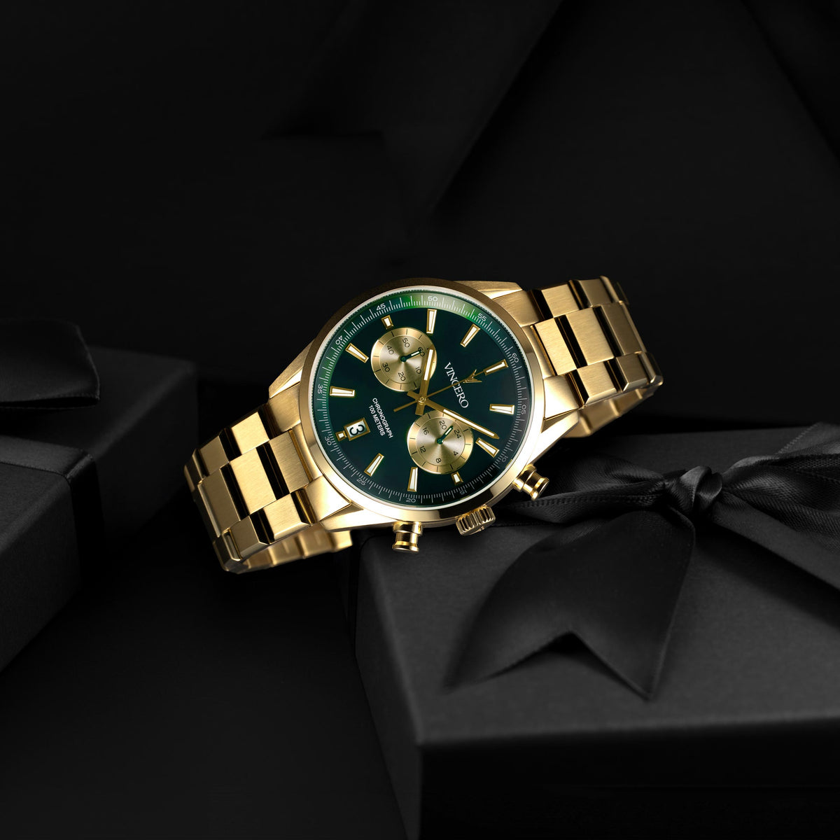 Gold wristwatch with a green face on a black background