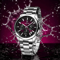 Silver watch with a dark face splashing water against a purple background