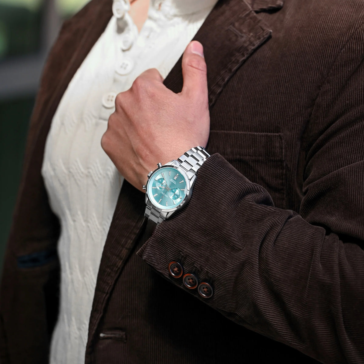 Man grabbing his jacket collar. wearing the Chrono Limited Release watch, featuring a Carolina blue face, stainless steel case, and matching steel band.