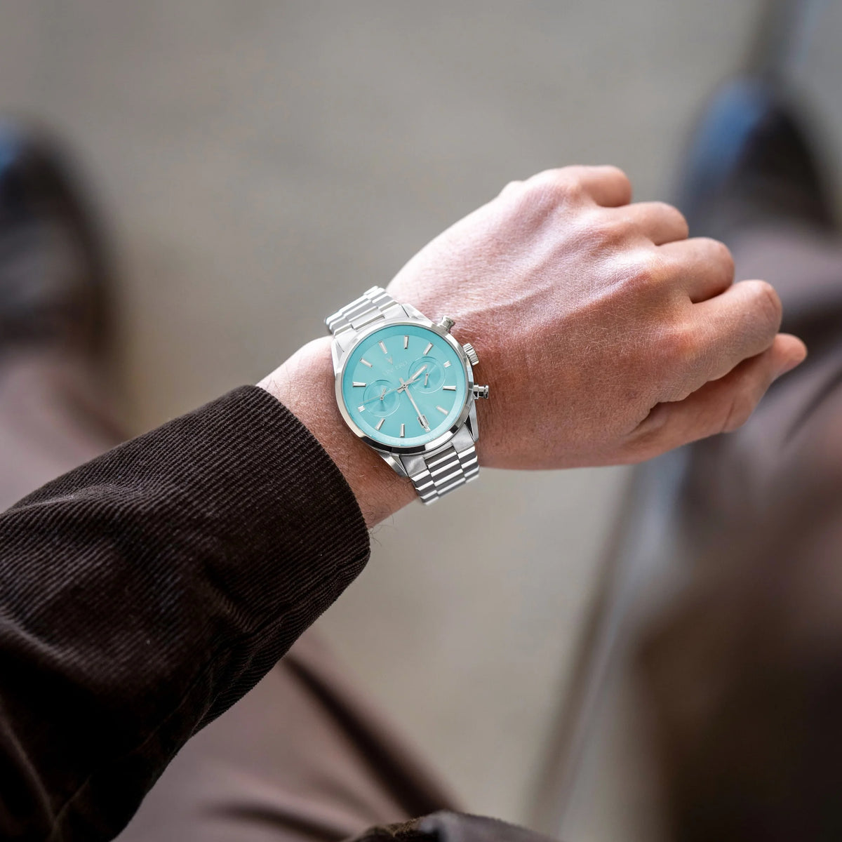Man showing his wrist wearing the Chrono Limited Release watch, featuring a Carolina blue face, stainless steel case, and matching steel band.