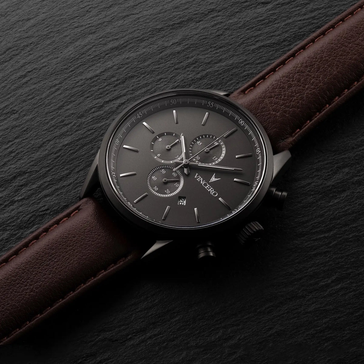 Wristwatch with brown leather strap and dark face on a dark background