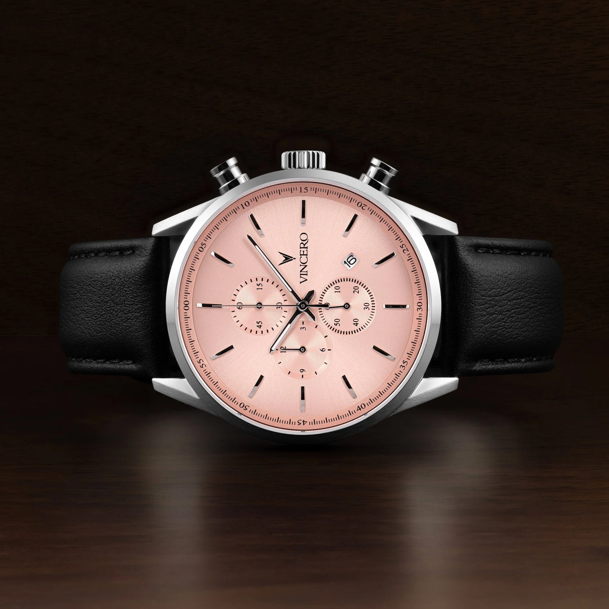 Luxury watch with a pink dial and black leather strap on a dark background