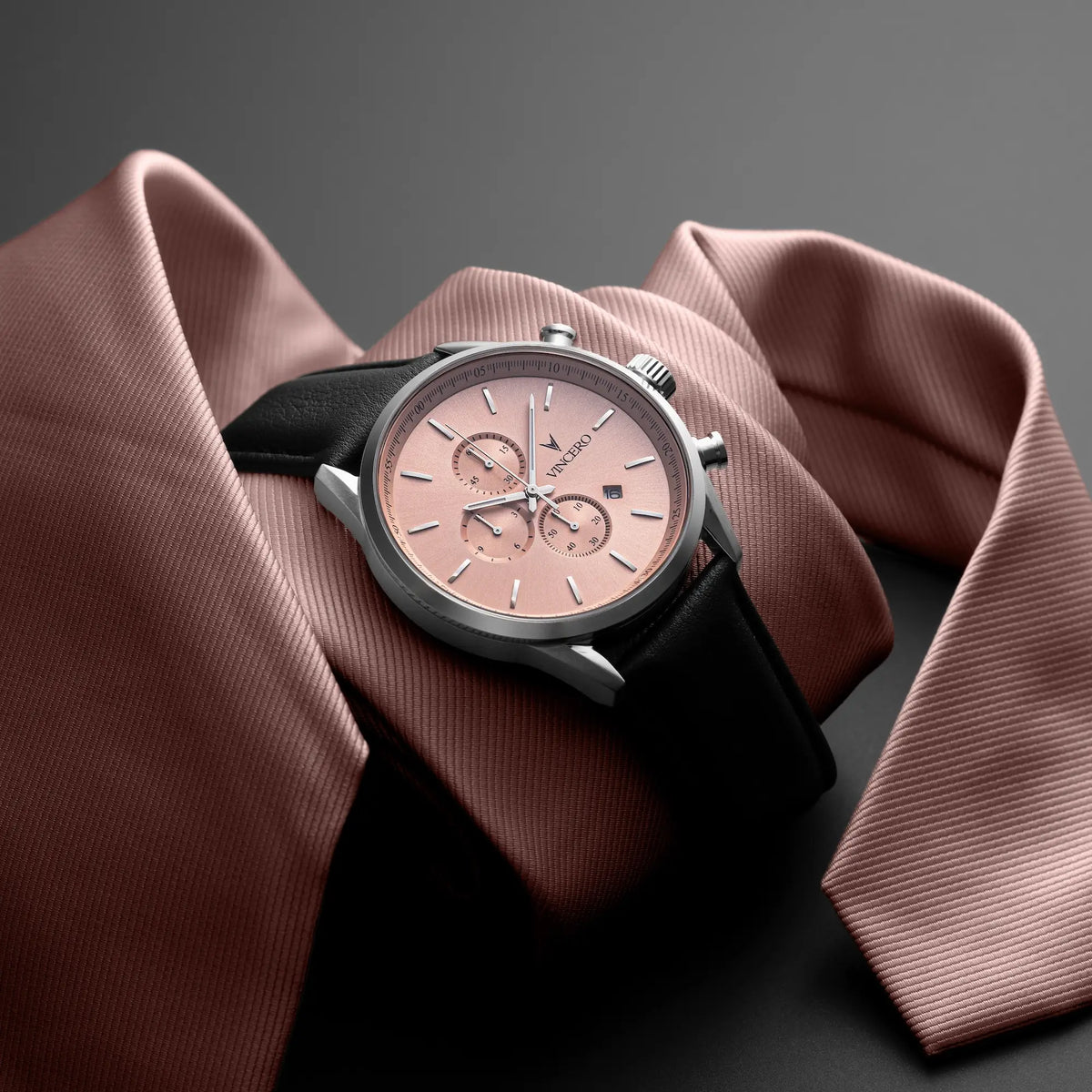 Wristwatch with black strap and pink dial on a brown fabric background