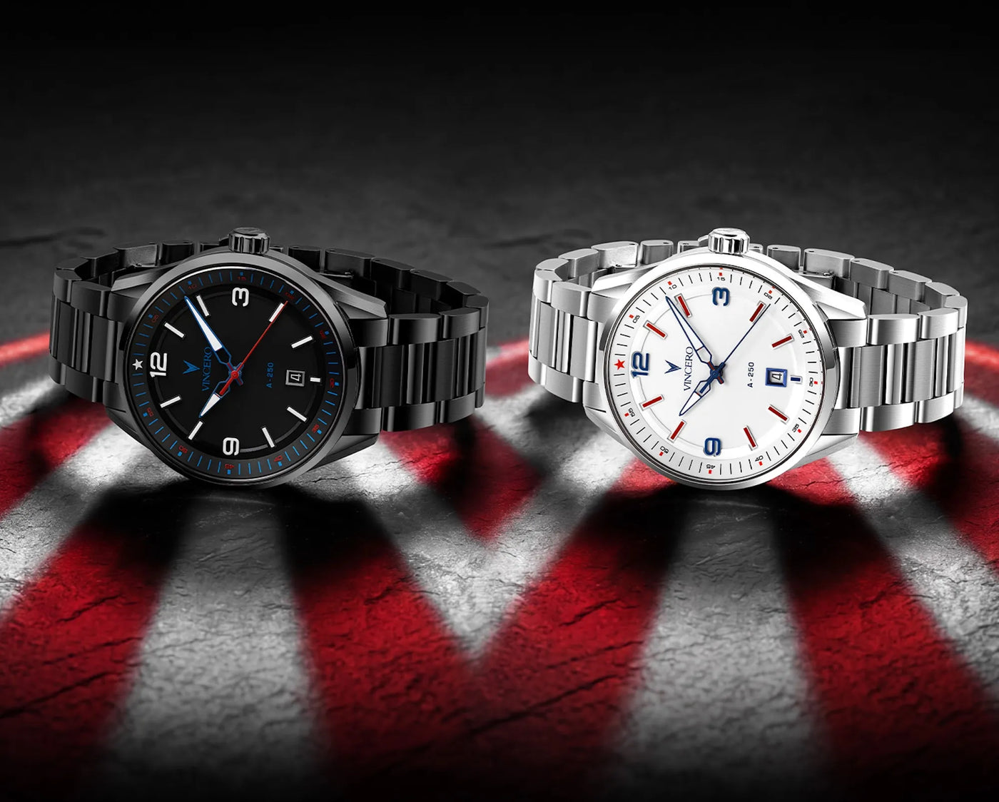 Two wristwatches displayed side by side on a dark textured surface with red and white streaks. One watch has a black dial and black metal bracelet, and the other has a white dial with red accents and a silver metal bracelet.