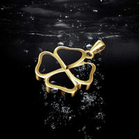 Gold four-leaf clover pendant on a reflective black surface