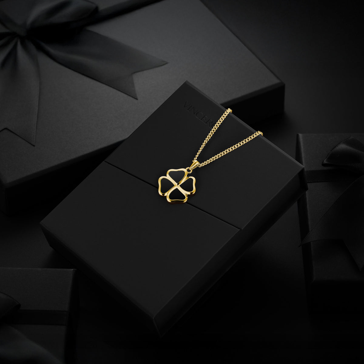 Gold necklace on a black box with a black background