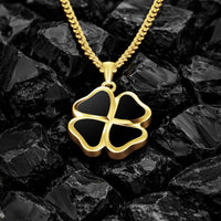 Gold four-leaf clover pendant necklace on a dark stone background