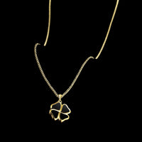 Gold necklace with a clover-shaped pendant on a black background