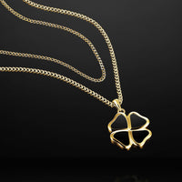Gold four-leaf clover pendant necklace on a black background