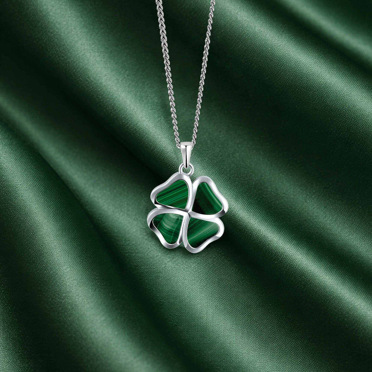 Four-leaf clover pendant necklace on a green satin background