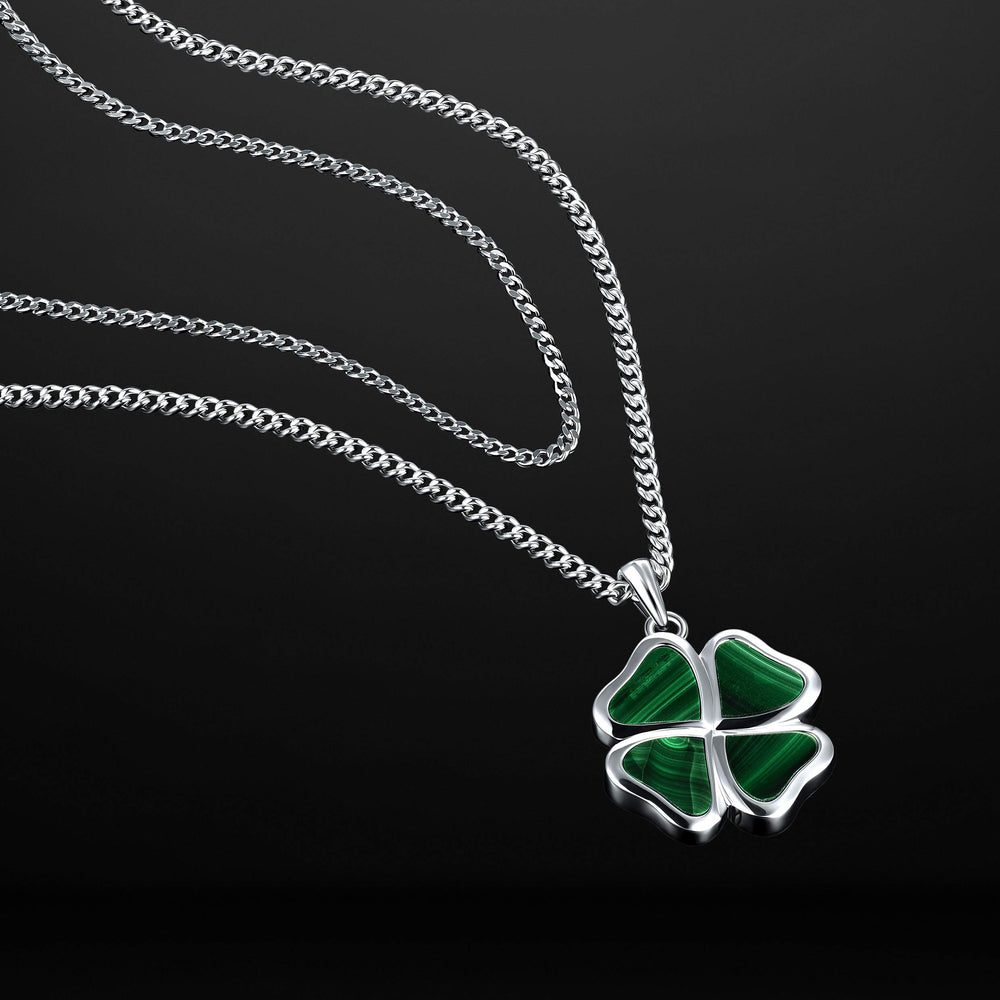 Four-leaf clover pendant on a silver chain against a black background