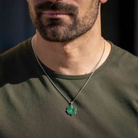 Man wearing a green clover pendant necklace against a dark background